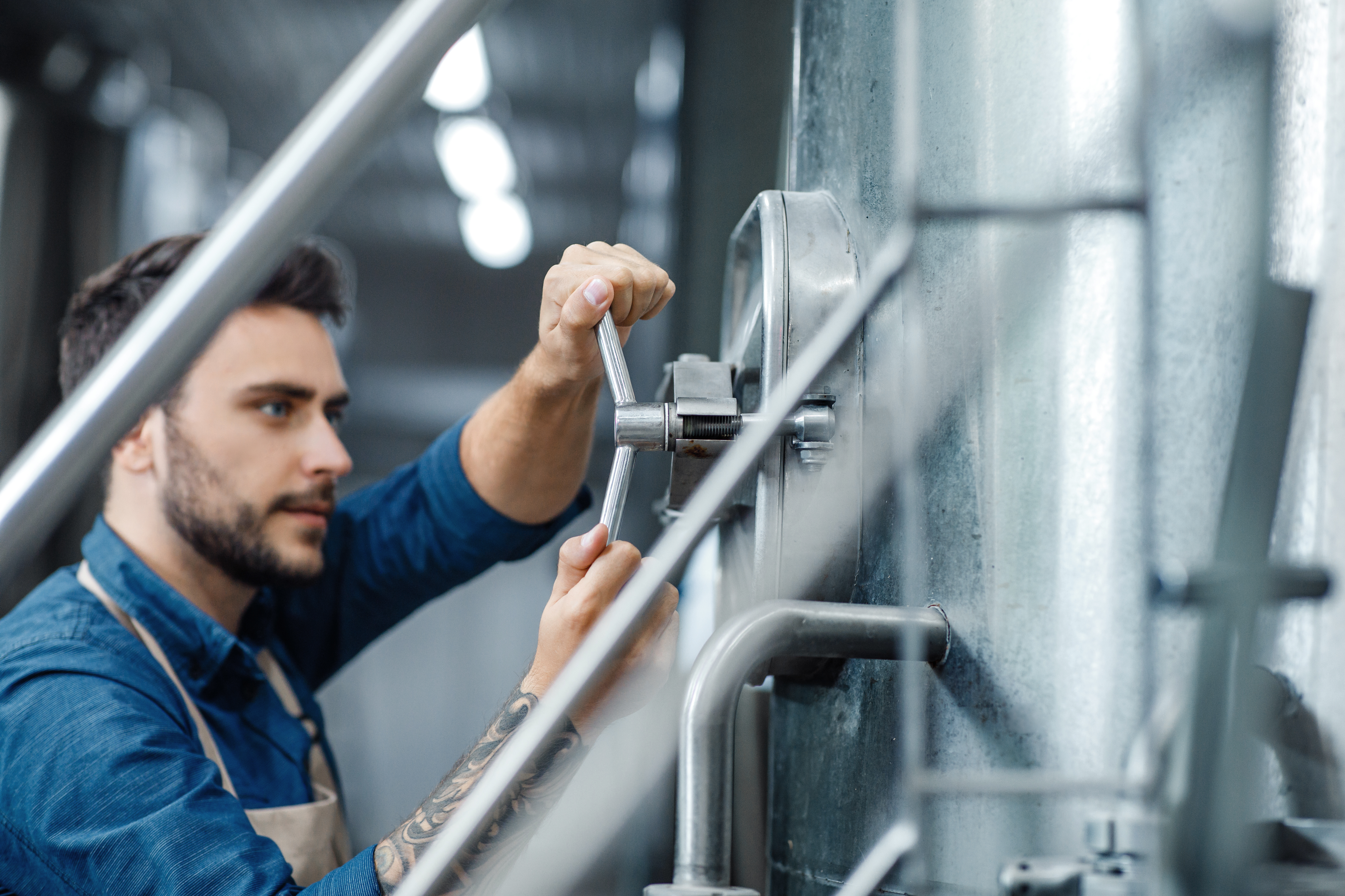 Male brewer turning valve in ale brewery